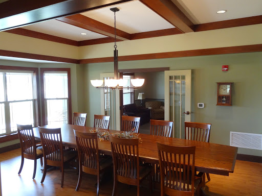 An elegant dining room featuring a long wooden table with matching chairs under a stylish chandelier.
