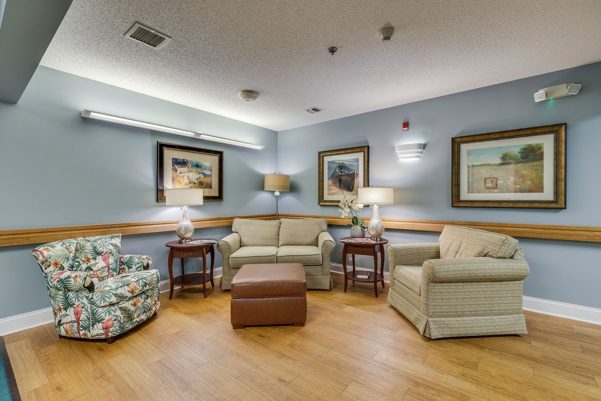 A cozy living room with sofas, armchairs, and decorative artwork on the walls.