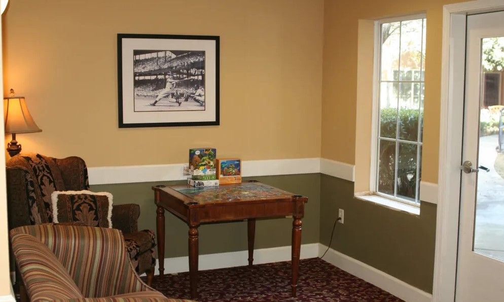 A cozy corner of a living room with a small table, picture frame on the wall, and a window letting in natural light.