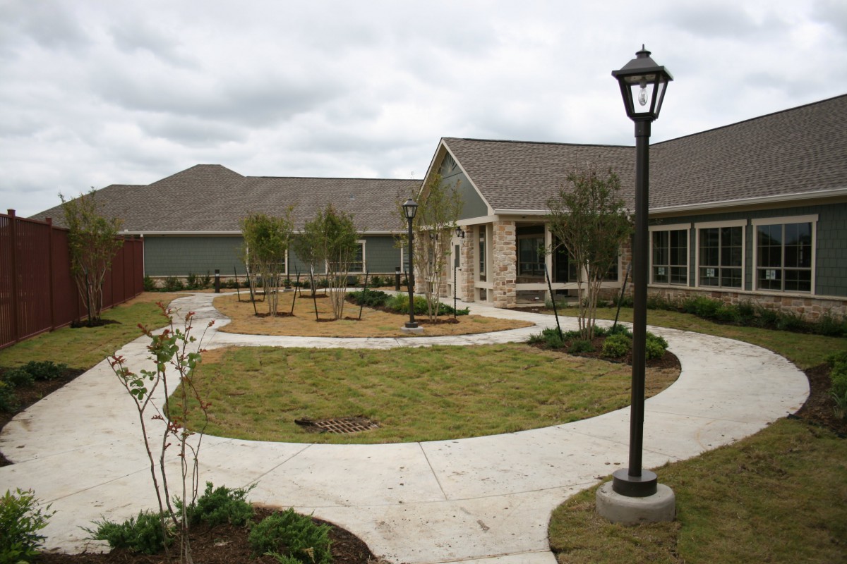 A modern building with a landscaped garden and pathway under a cloudy sky.