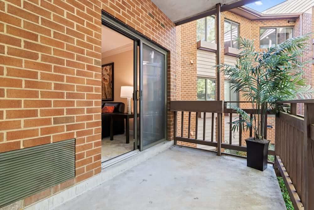 A cozy apartment balcony with a view of a sliding glass door and a potted plant.