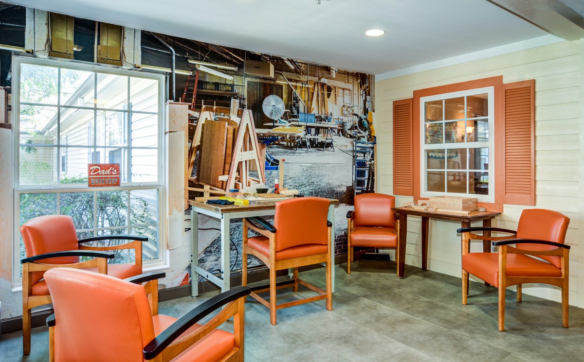 A cozy workshop with orange chairs and woodworking tools neatly arranged on the wall.