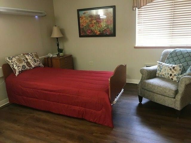 A cozy bedroom with a single bed, armchair, and decorative painting.