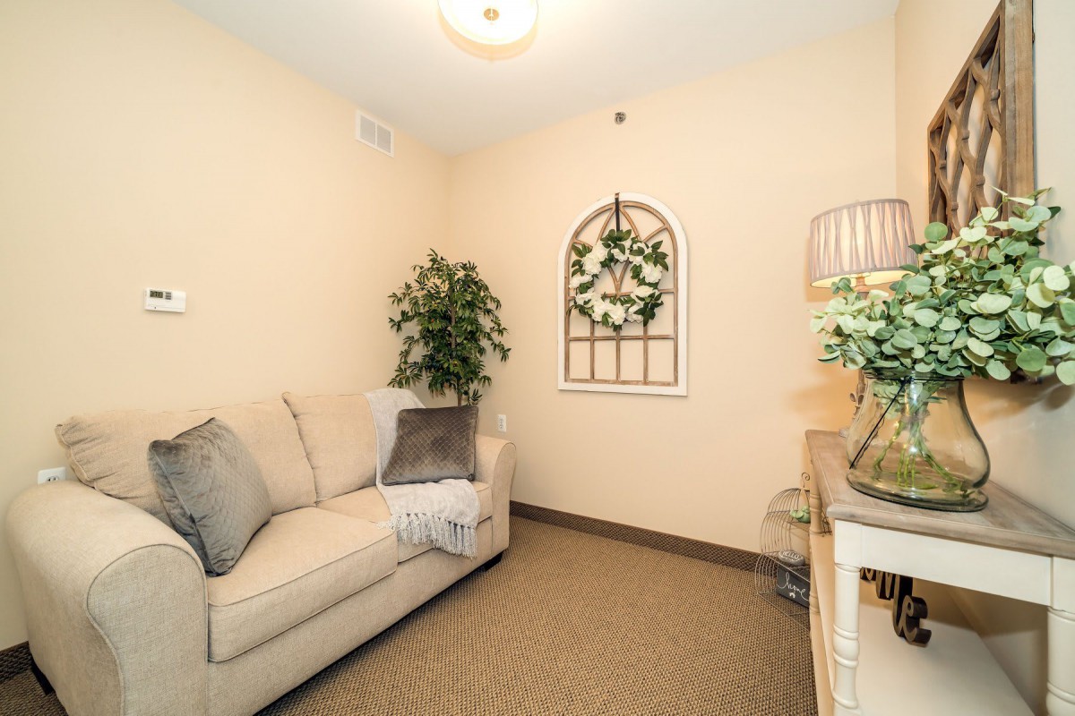 A cozy living room with a beige sofa, green plants, and elegant decor.