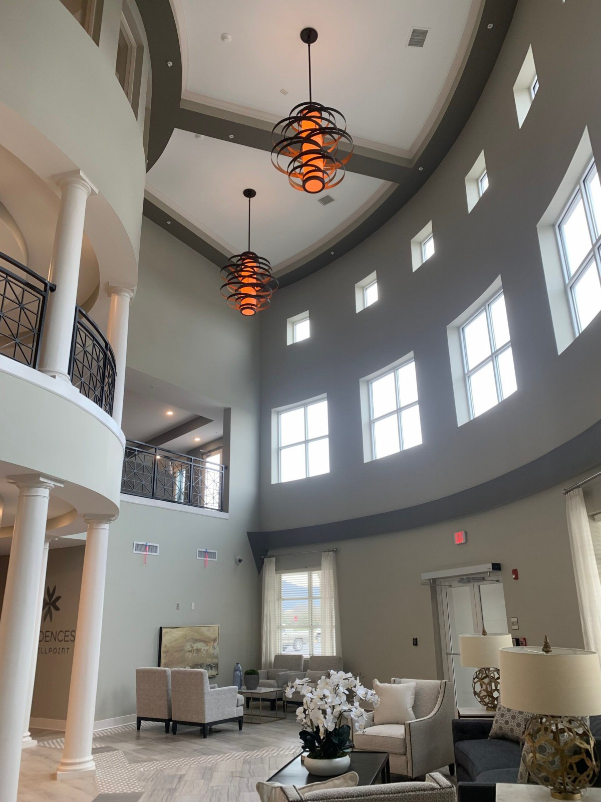 A spacious modern lobby featuring large windows and elegant chandeliers.