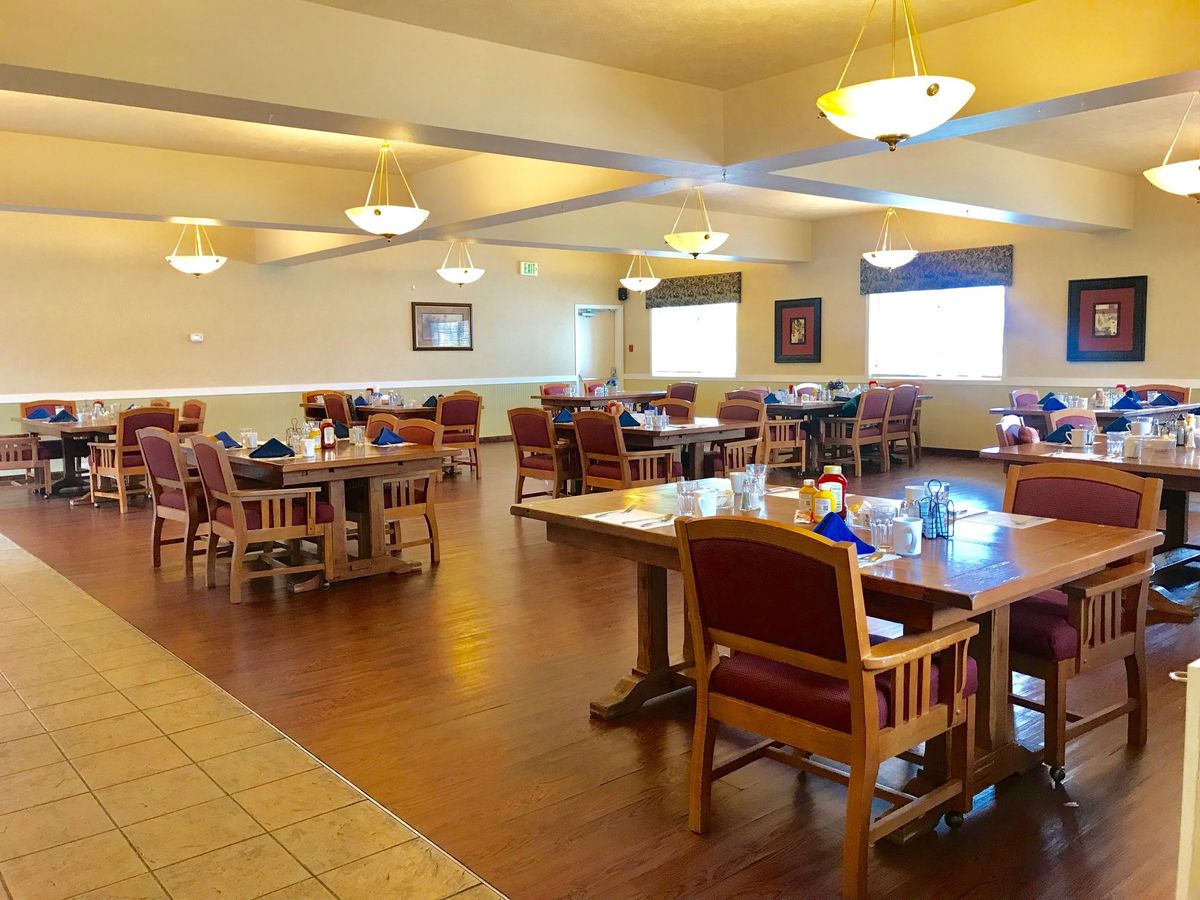 An empty dining room with neatly arranged tables and chairs under warm lighting.