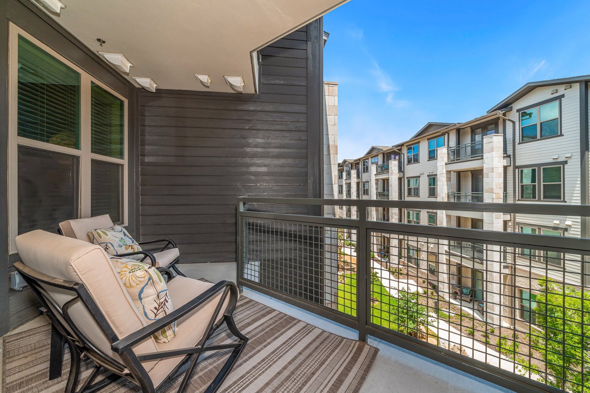 A modern balcony with patio furniture overlooking an apartment complex.