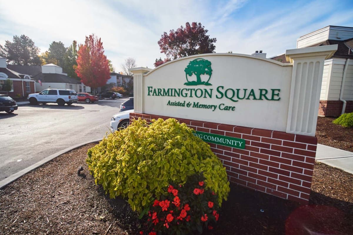 Entrance sign for Farmington Square Assisted & Memory Care surrounded by fall foliage and flowers.