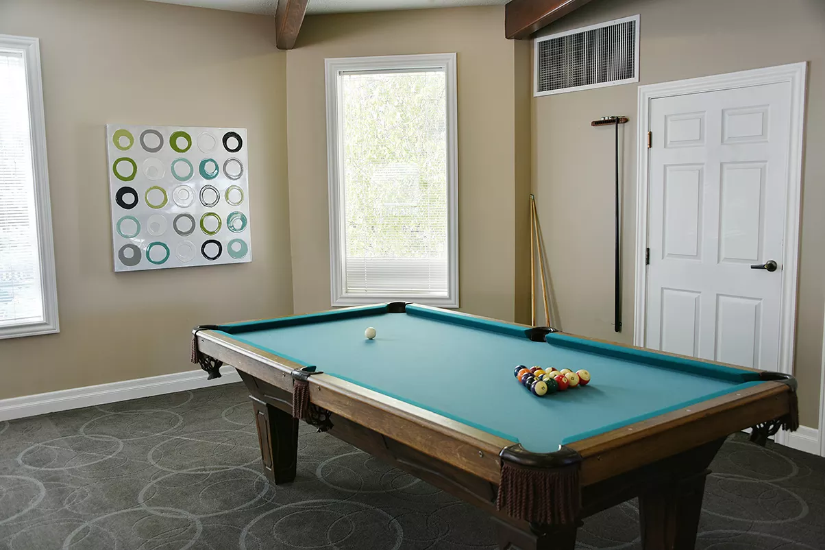 A billiards room featuring a pool table with cue sticks and a contemporary wall art piece.