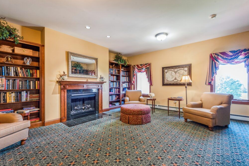 A cozy living room featuring a fireplace, comfortable sofas, and a stocked bookshelf.