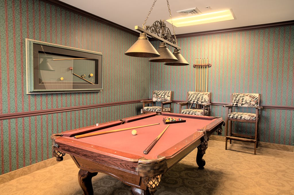 A cozy game room featuring a classic pool table and comfortable seating.