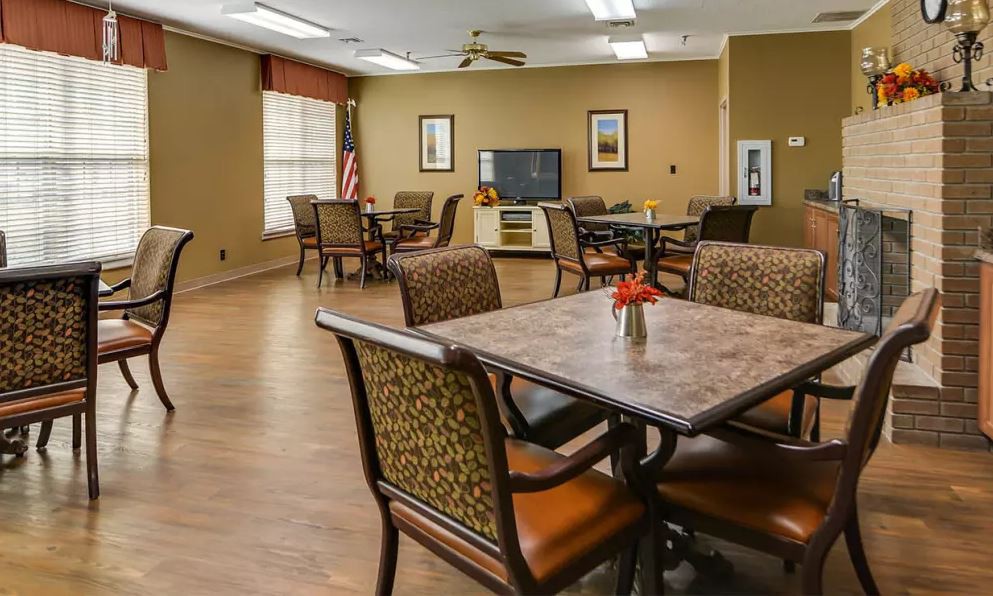 A communal dining area with several tables and chairs, a television, and decorative elements.