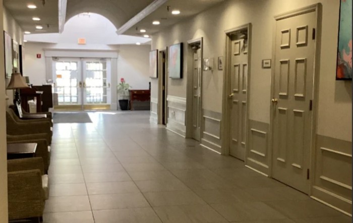 A well-lit hallway with several doors and a tile floor leading to an entrance.