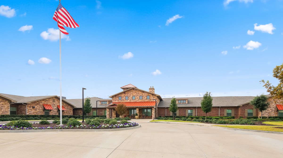 A large building with an American flag flying above, set against a clear blue sky.