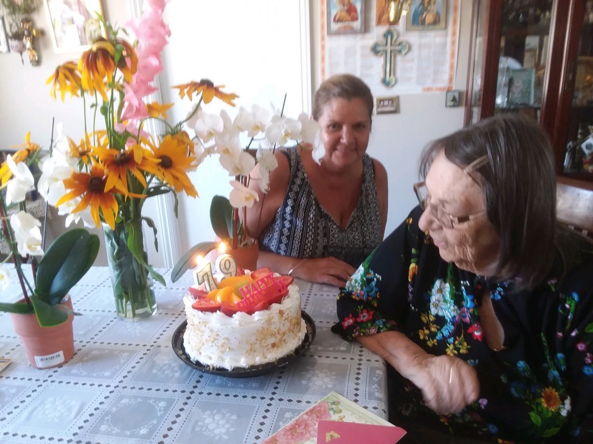 Two people celebrating a birthday with a decorated cake and flowers on the table.