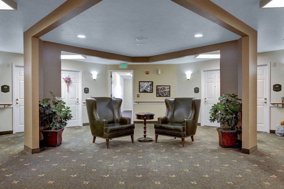 A cozy lobby area with two armchairs, a small table, and decorative plants.