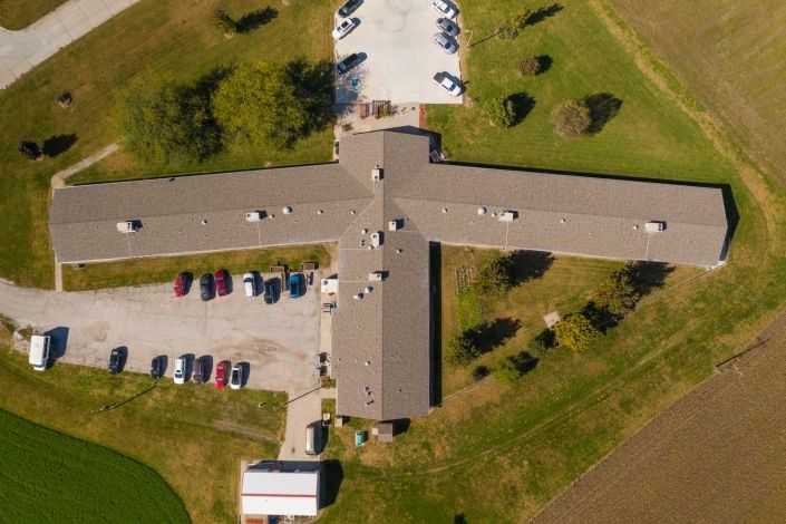 An aerial view of a building surrounded by a parking lot and greenery.