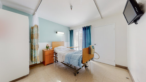 A well-lit hospital patient room featuring a bed, dresser, and curtains.
