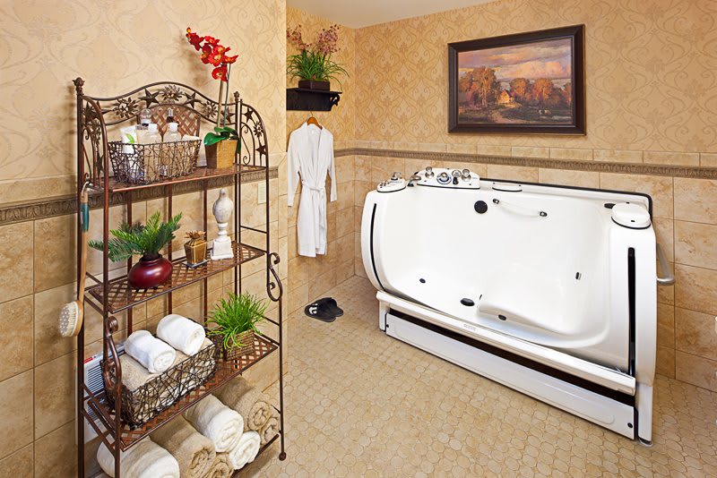 A well-decorated bathroom featuring a modern bathtub, neatly arranged towels on shelves, and lush green plants for a fresh ambiance.