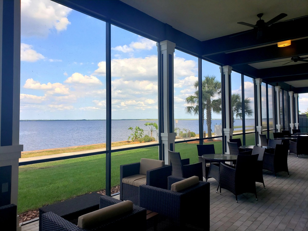 A scenic patio with outdoor seating overlooking a beautiful waterfront and palm trees.
