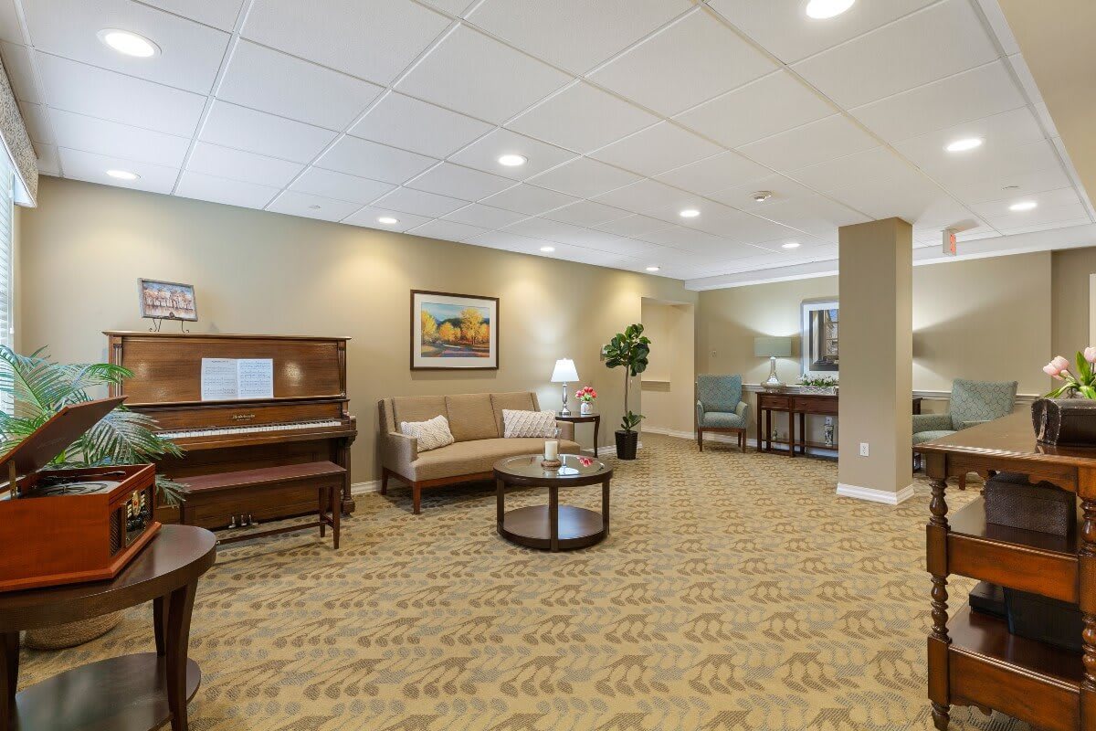 A spacious lounge area featuring a piano, sofa, and coffee table with artwork on the walls.