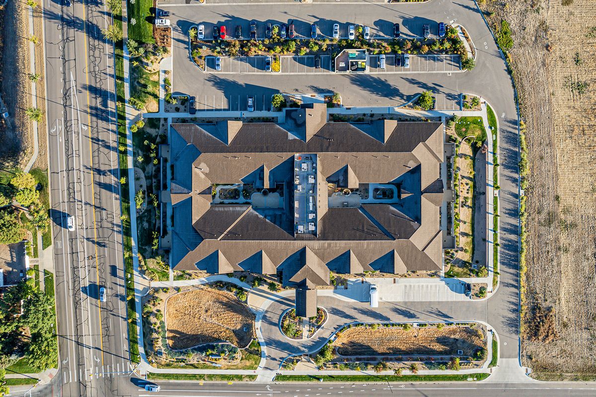 Aerial view of a large building with a surrounding parking lot and landscaped areas.