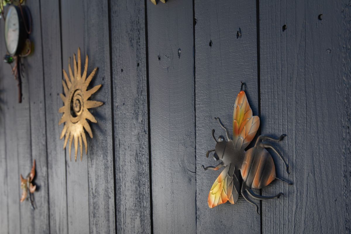 Metal sun and butterfly wall decorations on a wooden surface.