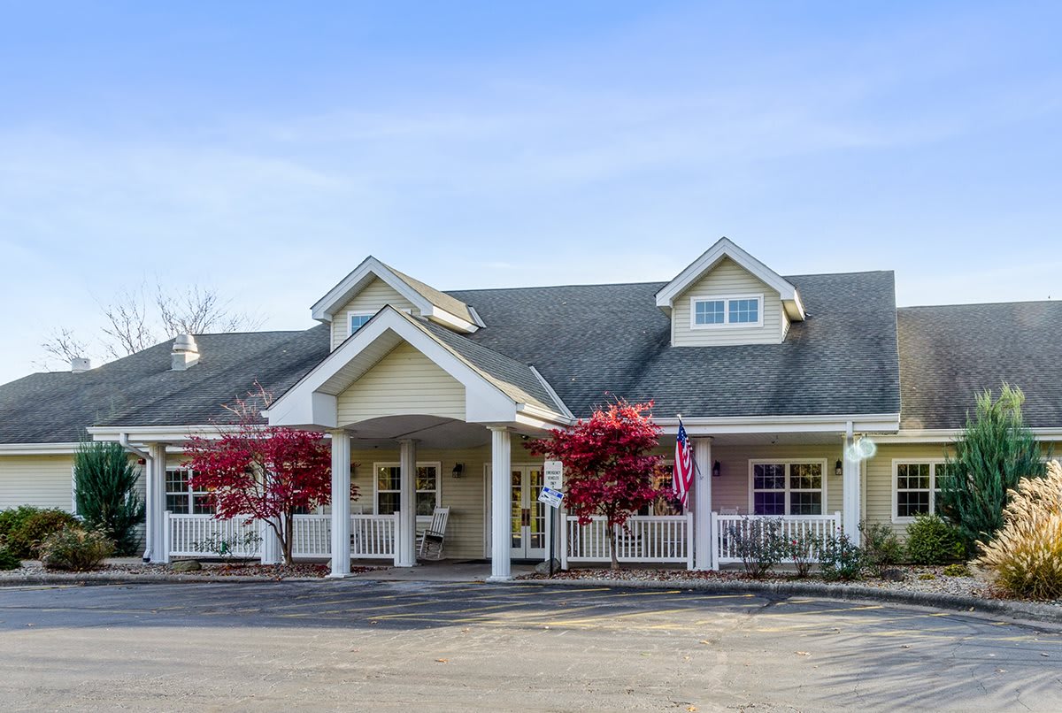 A charming residential building with a covered entrance and vibrant trees in front.