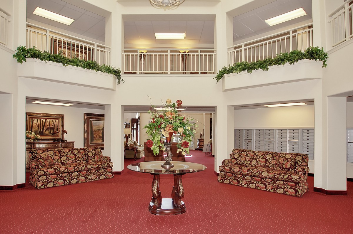 A spacious lobby with elegant furniture and floral centerpiece.