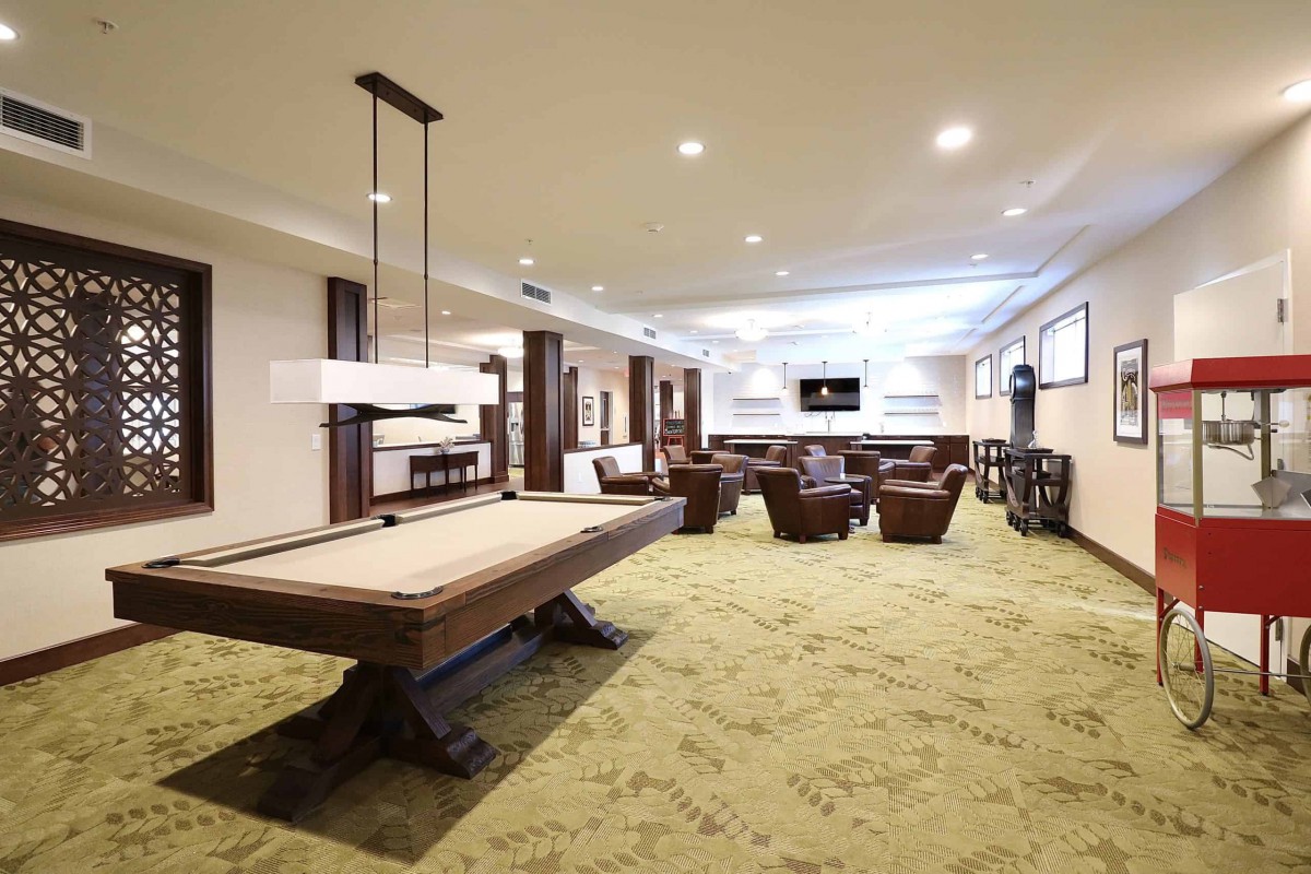 Spacious recreation room featuring a billiards table and comfortable seating with a modern design.