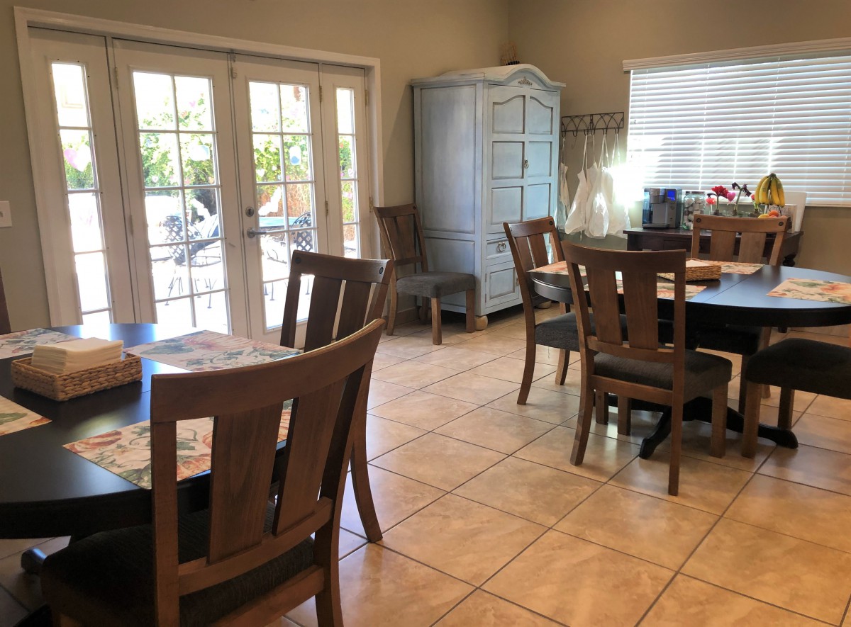 A cozy dining area with wooden furniture and large windows allowing natural light to fill the space.