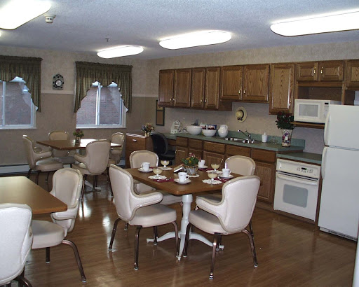 A cozy kitchen and dining area with wooden cabinets, a round table set for meals, and ample lighting.