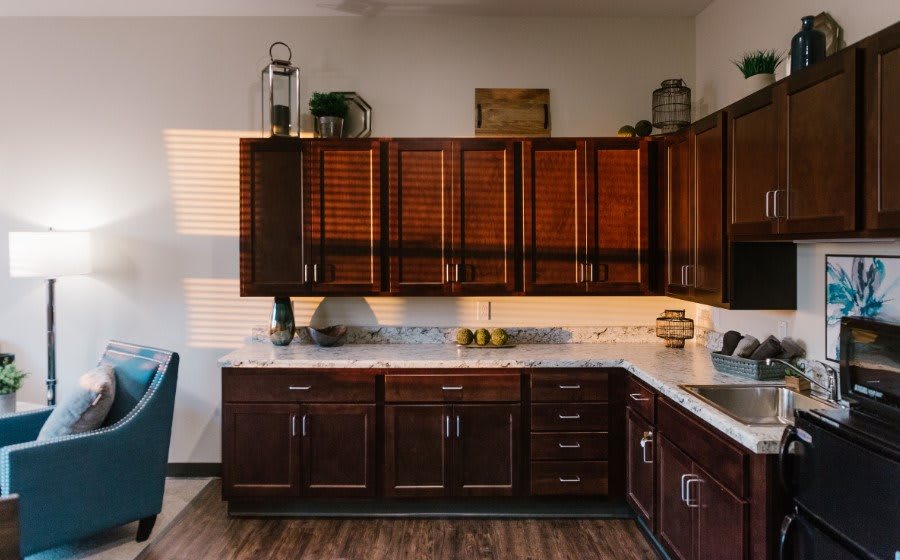 A modern kitchen with dark wood cabinets and a marble countertop.