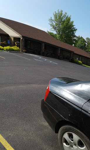 A parked car in front of a building with landscaped surroundings.