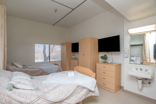 A well-furnished bedroom featuring two beds, modern cabinets, and televisions.
