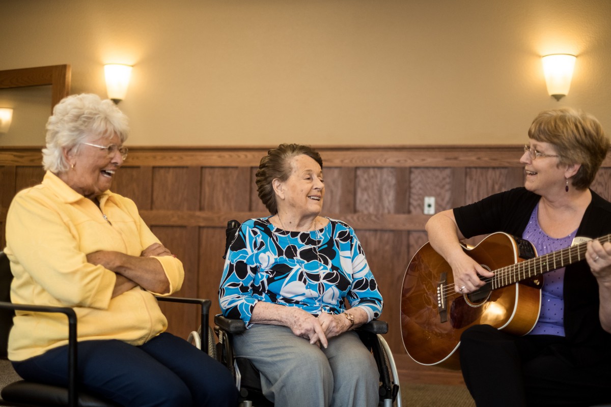 A group of seniors enjoying a music session, with one playing the guitar.