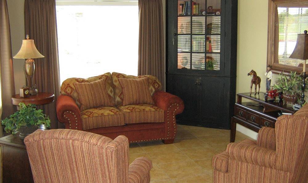 A cozy living room with a sofa, armchair, and a bookshelf in the corner.