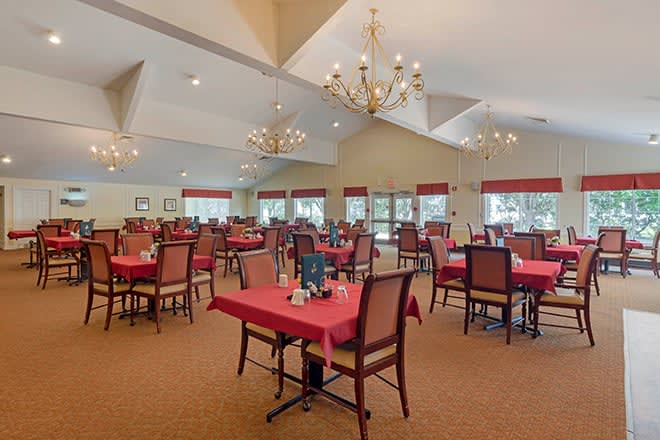 A spacious dining room with elegantly set tables and chandeliers.