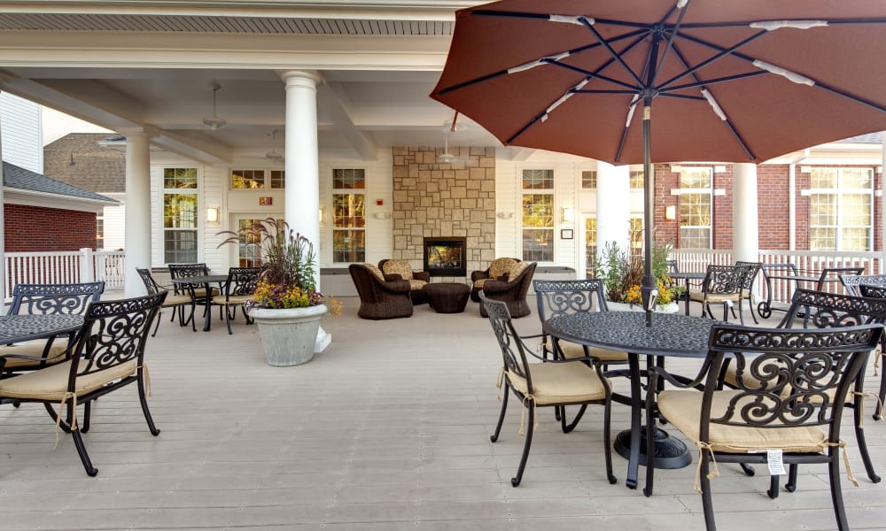 An inviting patio area with tables, chairs, and a central fireplace under a large umbrella.