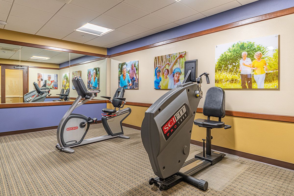 A small gym room featuring exercise bikes and colorful artwork on the walls.