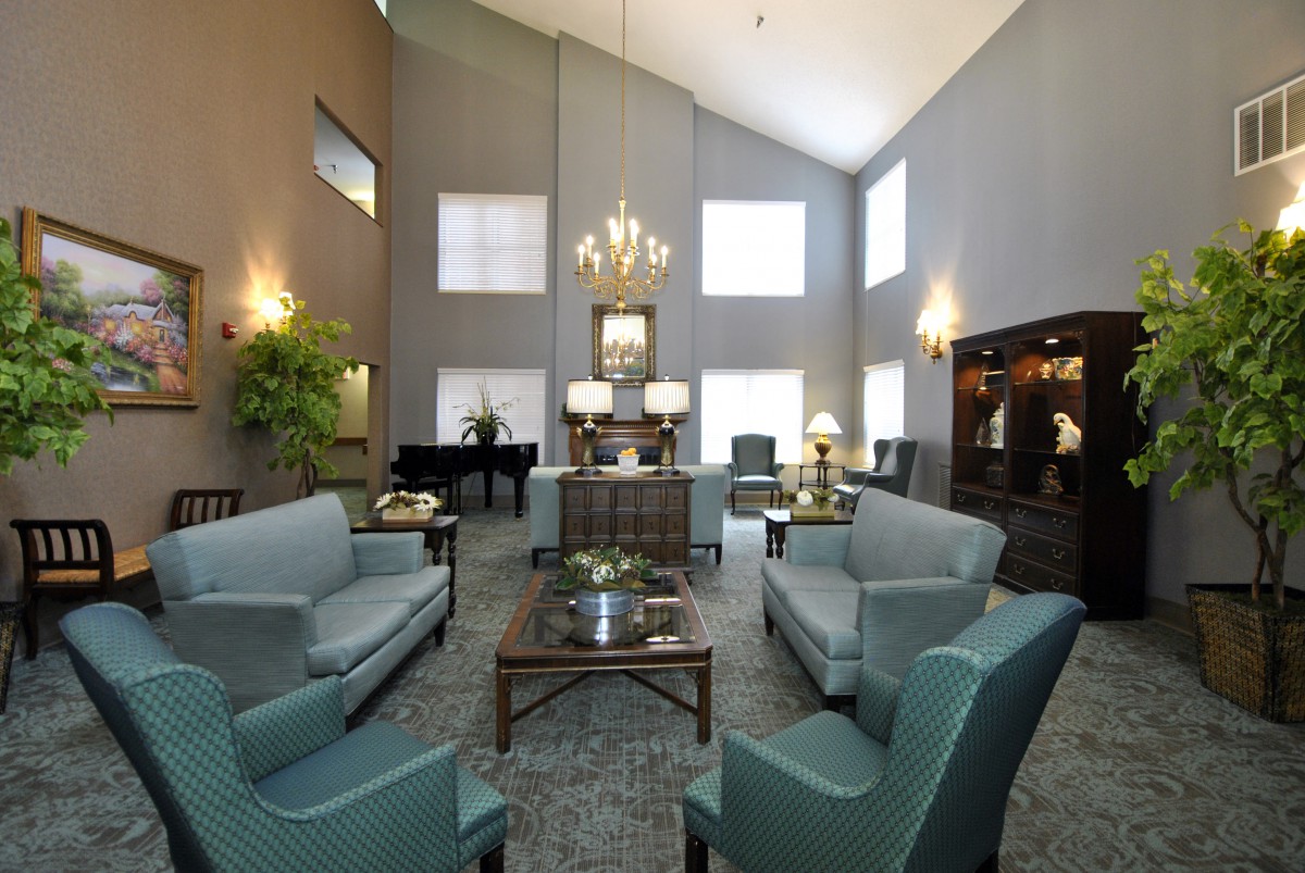 A spacious living room with elegant furniture, chandelier lighting, and a grand piano.