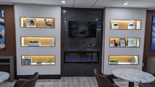 A stylish modern interior featuring illuminated shelves, a television, and an elegant fireplace.