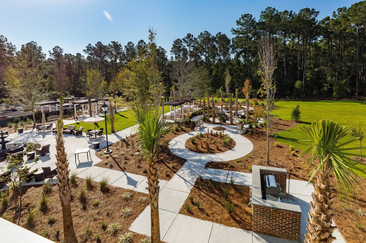 A beautifully landscaped park with winding pathways and seating areas surrounded by trees.