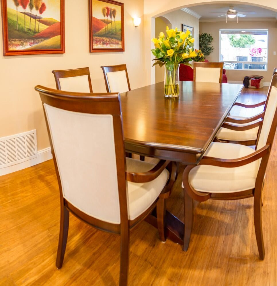 A well-designed dining room with a wooden table and chairs, complemented by floral decor and artwork on the walls.