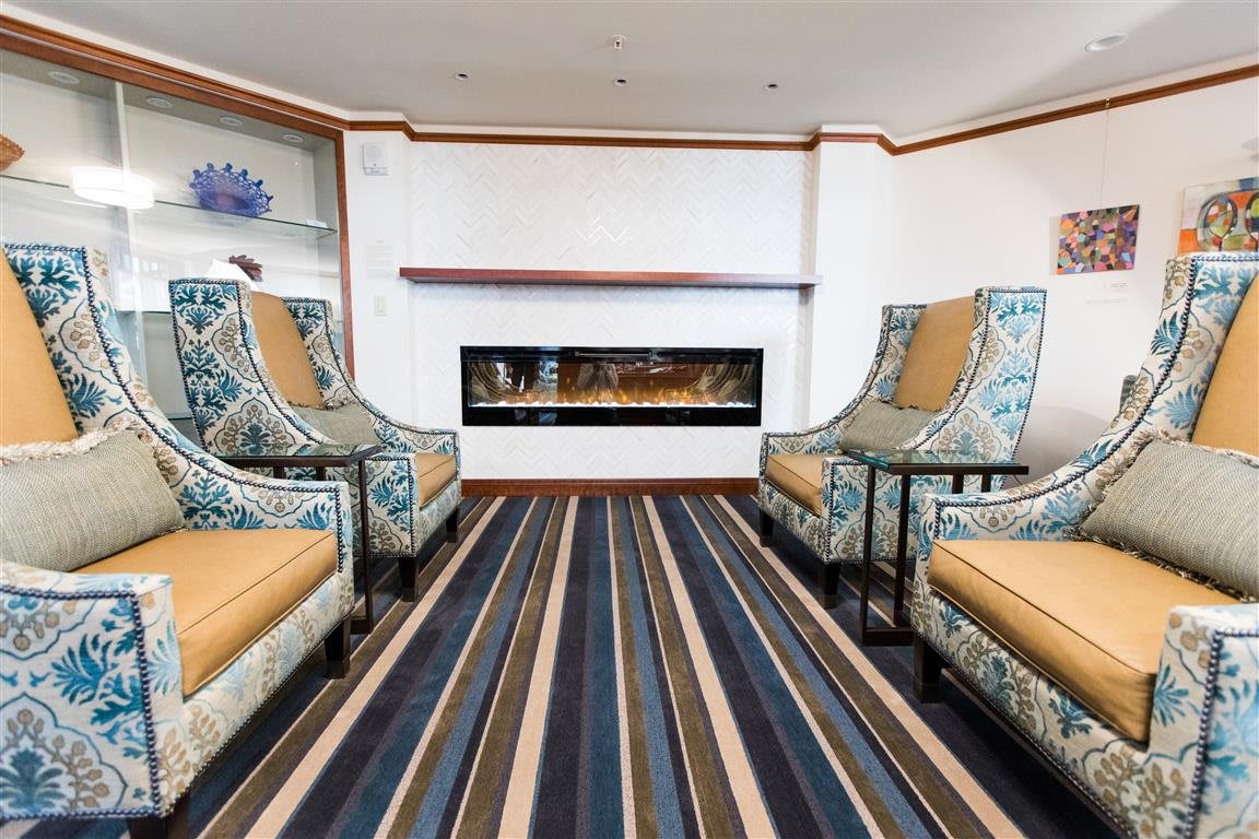 A modern living room with patterned chairs and a striped carpet, featuring a sleek fireplace.