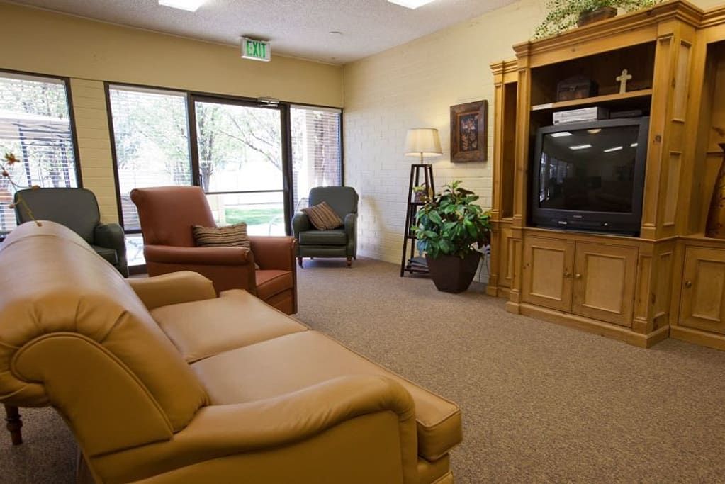 A cozy living room with comfortable seating, a TV, and indoor plants.