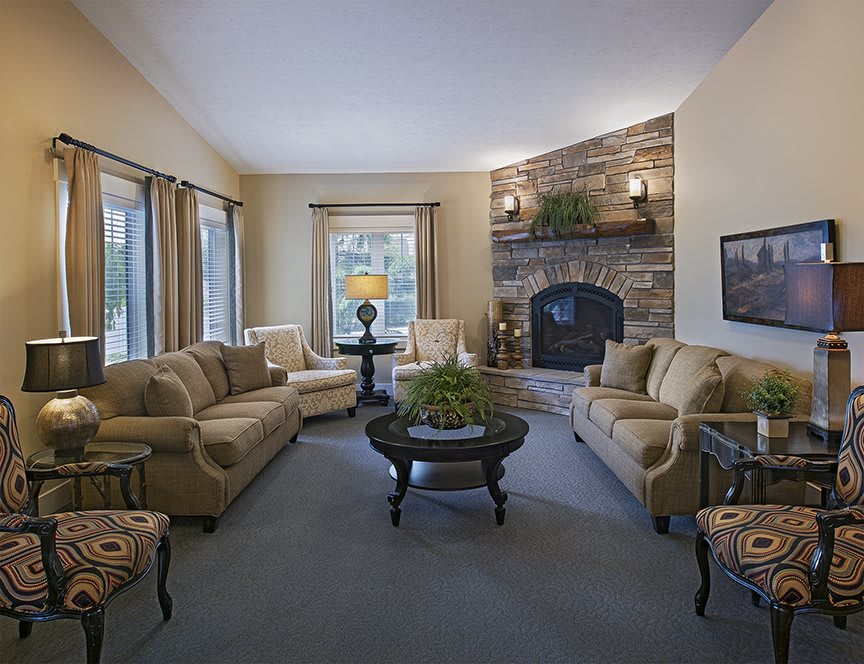 A cozy living room featuring plush sofas, a central coffee table, and a stone fireplace.