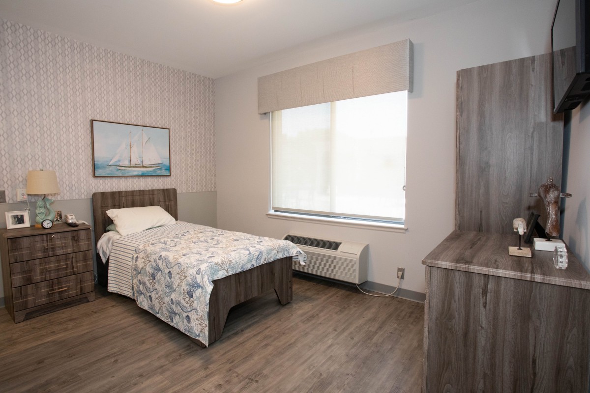 A modern, minimalist bedroom with a single bed and hardwood flooring.