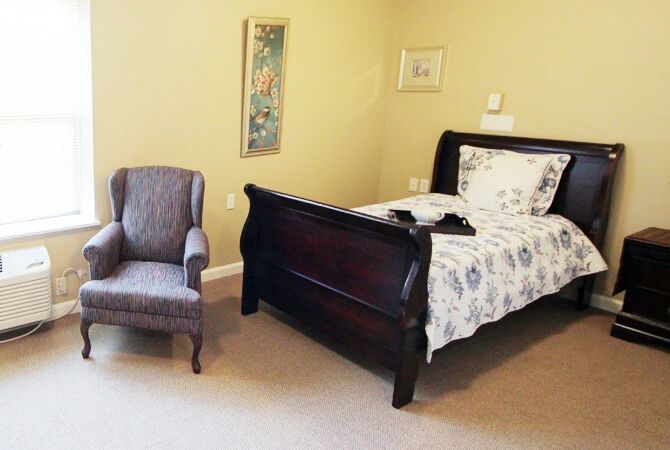 A cozy bedroom with a dark wooden bed and an upholstered armchair.