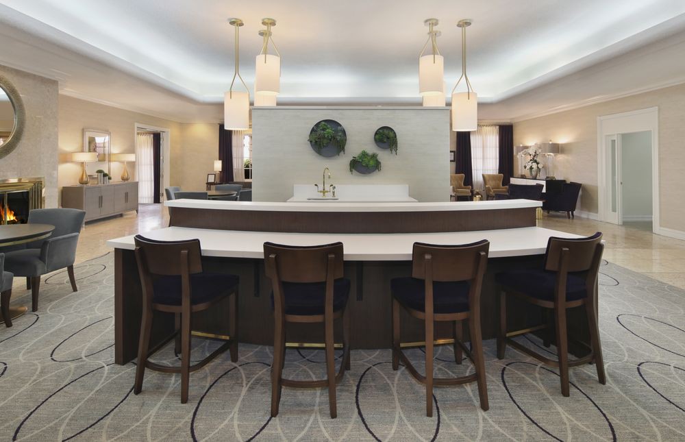 A modern kitchen interior with a sleek countertop and seating area, featuring pendant lights and decorative wall elements.